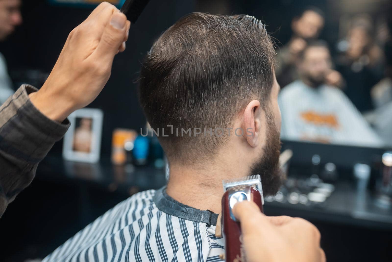 Master in barbershop makes men's haircutting with hair clipper by teksomolika