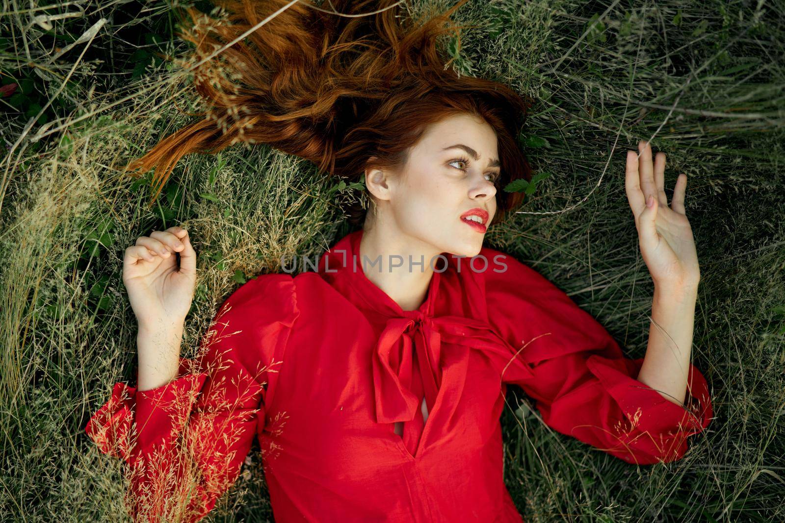 pretty woman in red dress lies on the grass landscape freedom. High quality photo