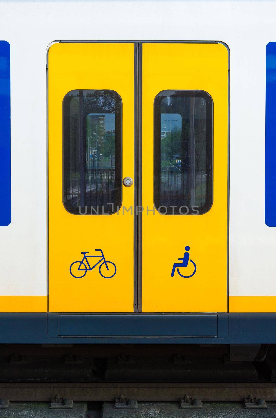Door of yellow train in railway station in the Netherlands. by Nuamfolio