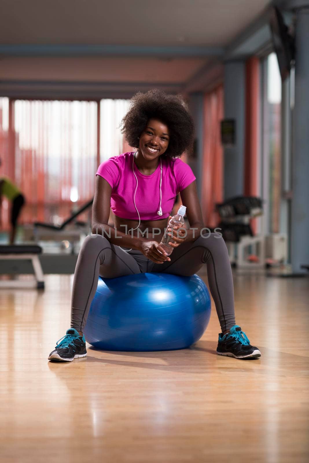 happy african american woman with a curly afro hairstyle in a  gym relaxing after pilates workout