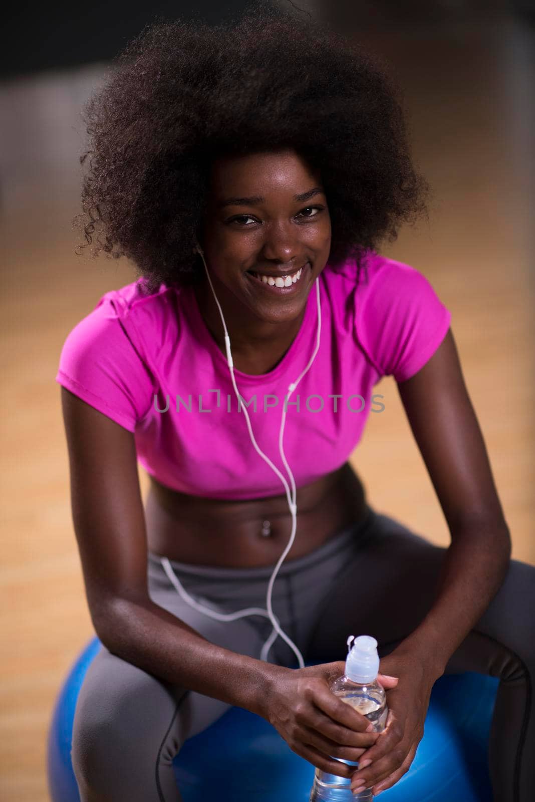 happy african american woman with a curly afro hairstyle in a  gym relaxing after pilates workout