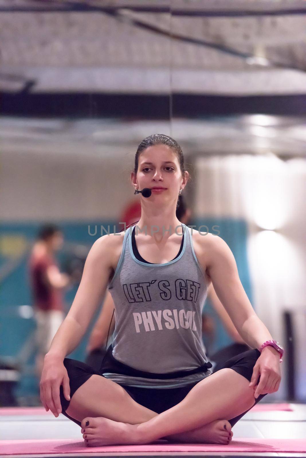 Relaxed young sportswoman doing yoga exercise and meditating in a fitness studio