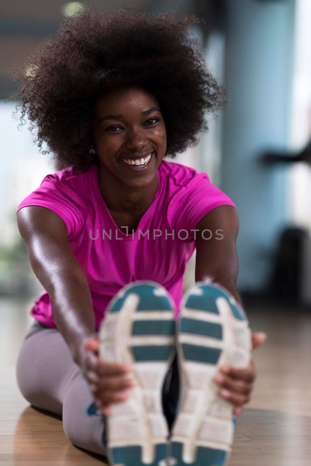 woman in a gym stretching and warming up before workout by dotshock