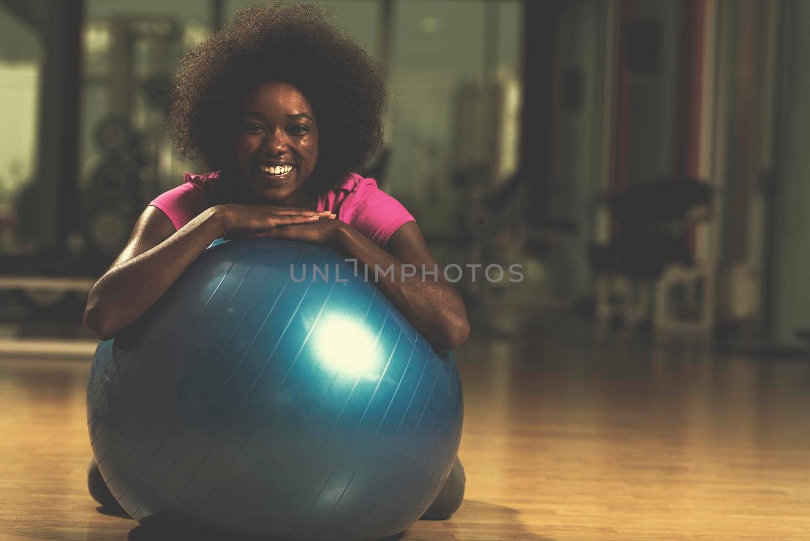 happy african american woman with a curly afro hairstyle in a  gym relaxing after pilates workout