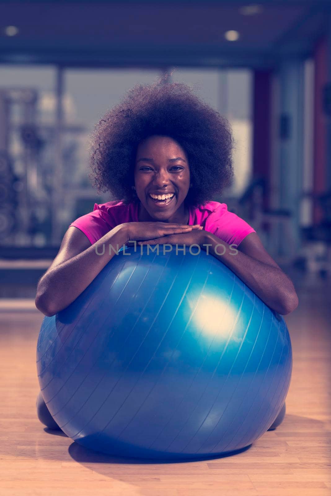 happy african american woman with a curly afro hairstyle in a  gym relaxing after pilates workout