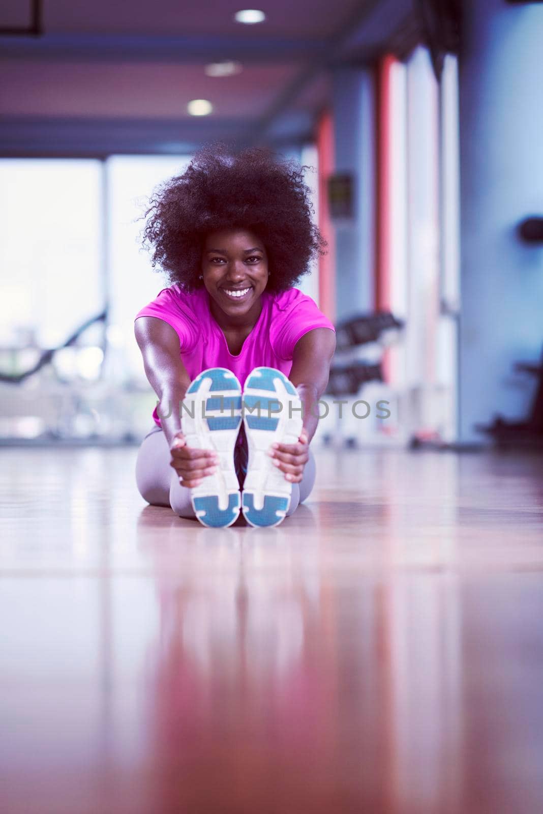 woman in a gym stretching and warming up before workout by dotshock