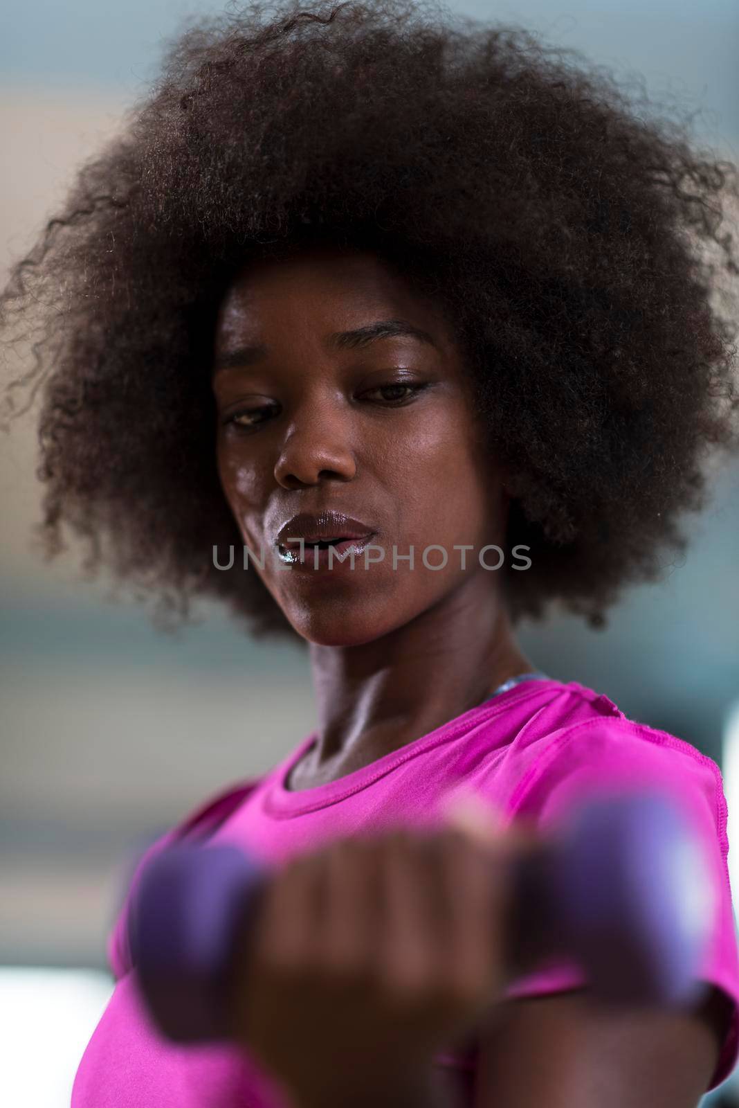 happy healthy african american woman working out in a crossfit gym on weight loss with dumbbells