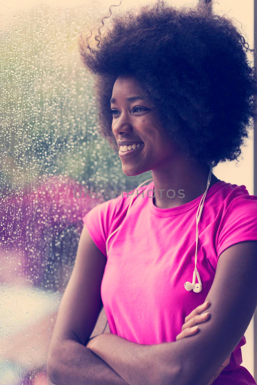 portrait of young afro american woman in gym on workout break while listening music on earphone  and dancing  rainy day and bad weather outdooor