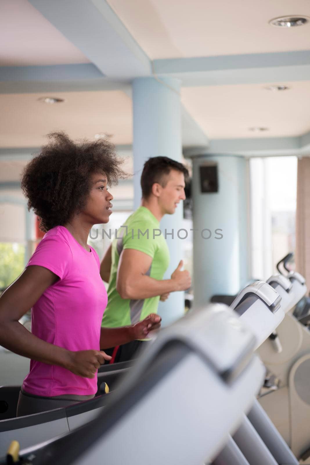 young people exercisinng a cardio on treadmill running chine in modern gym