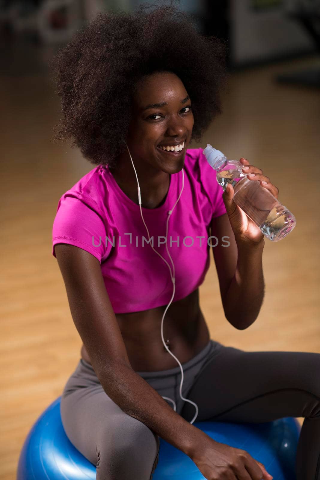 happy african american woman with a curly afro hairstyle in a  gym relaxing after pilates workout