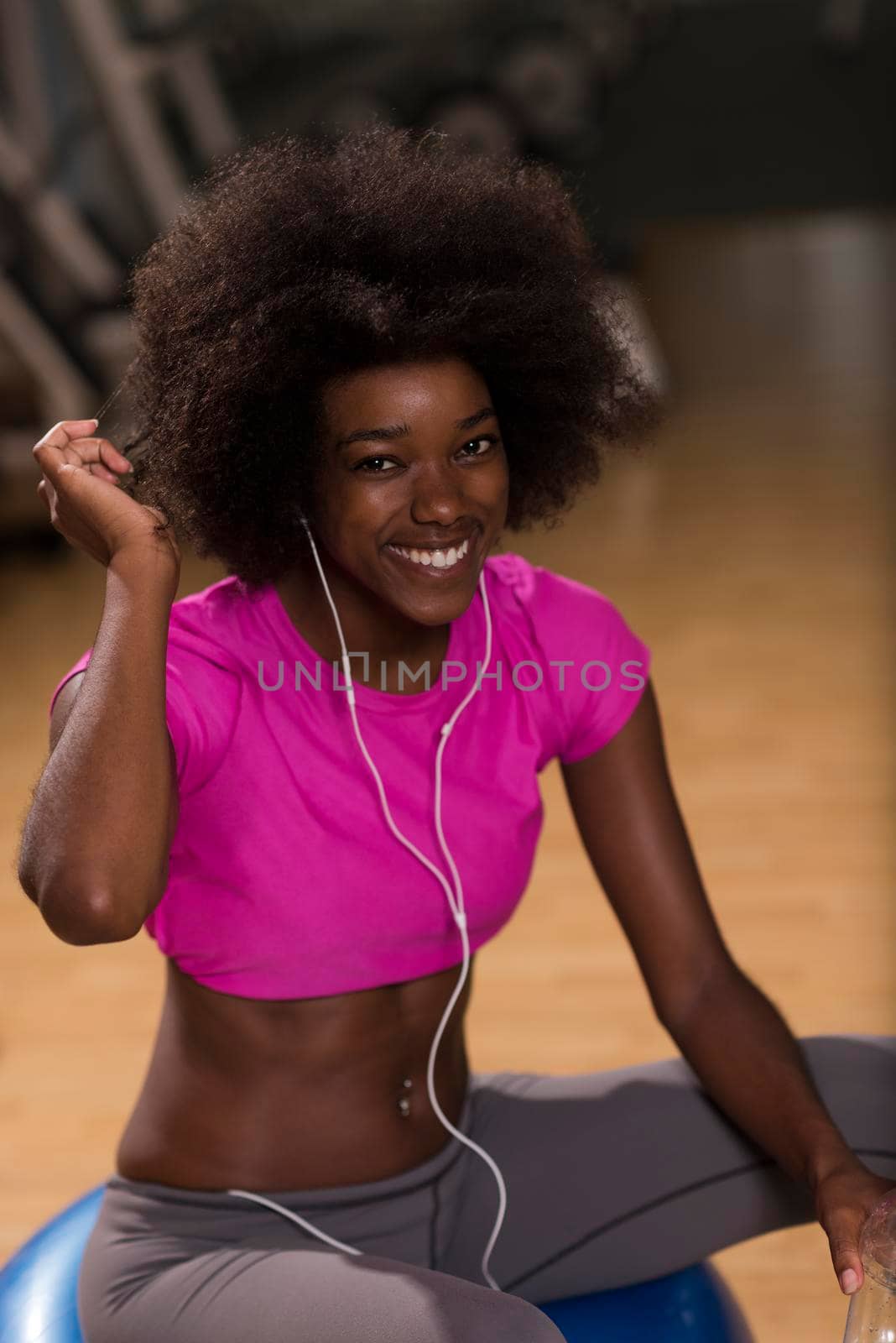 happy african american woman with a curly afro hairstyle in a  gym relaxing after pilates workout