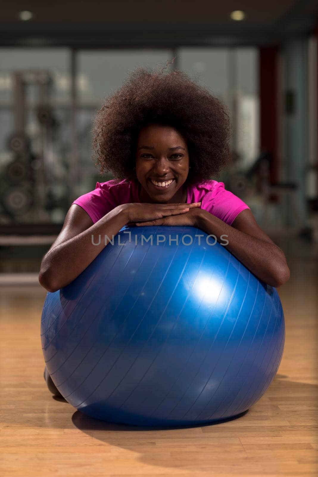 happy african american woman with a curly afro hairstyle in a  gym relaxing after pilates workout