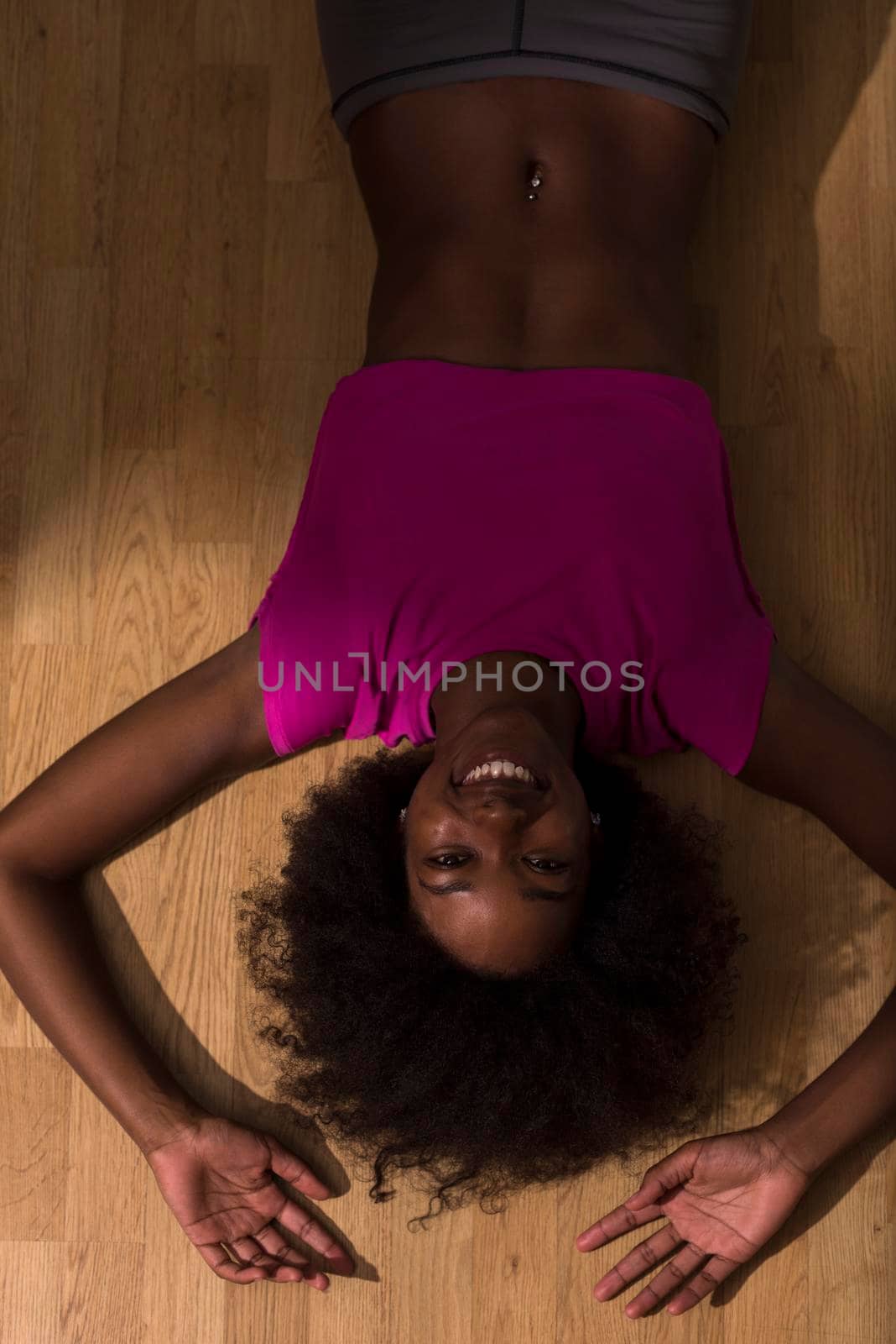 happy african american woman with a curly afro hairstyle in a  gym relaxing after pilates workout