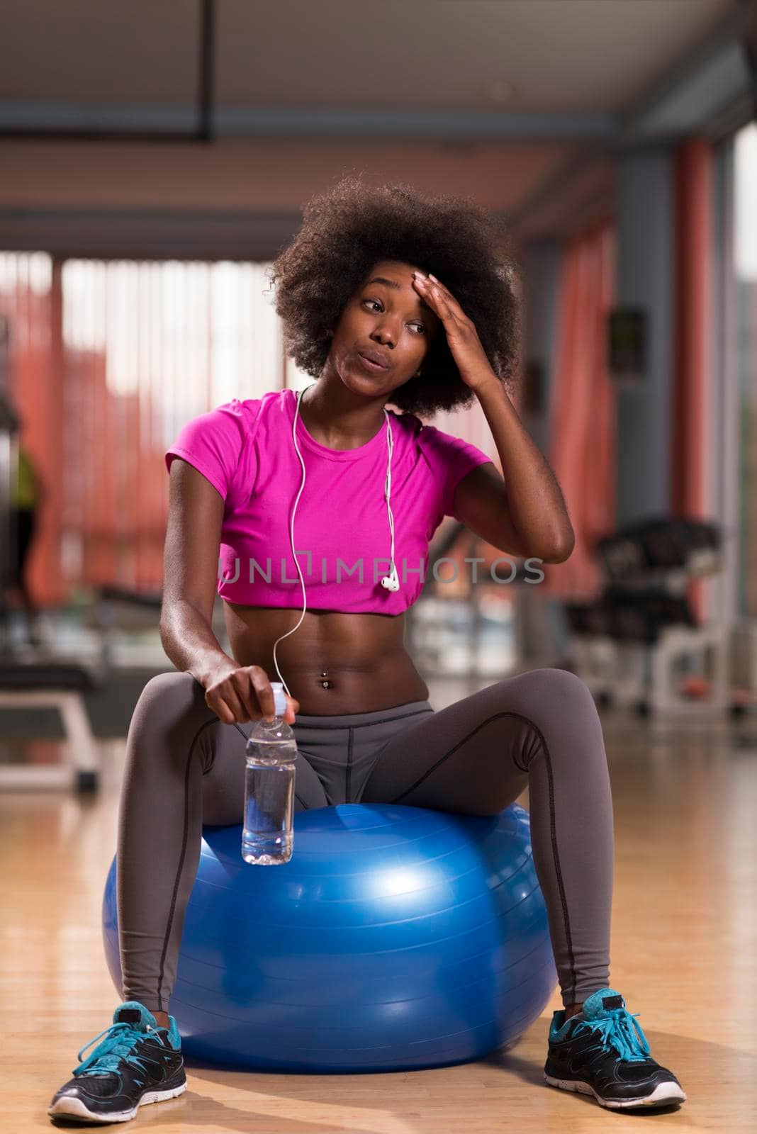 happy african american woman with a curly afro hairstyle in a  gym relaxing after pilates workout