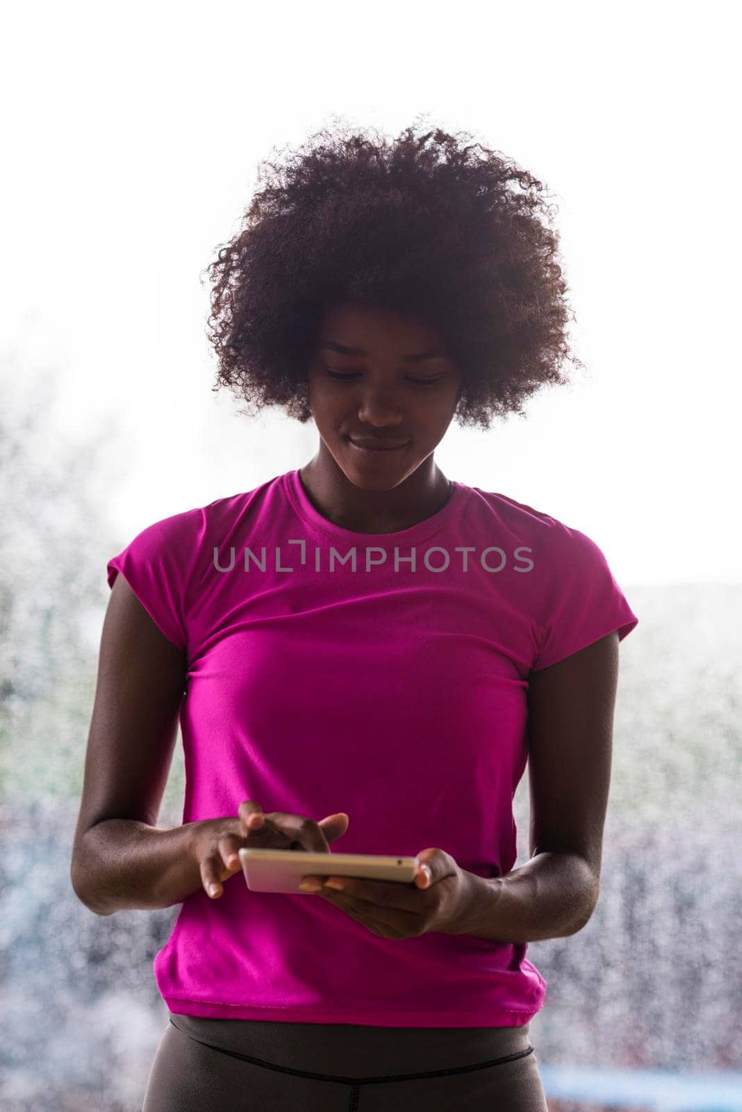 beautiful african american woman using tablet computer from home while rain and bad weather is outdoor