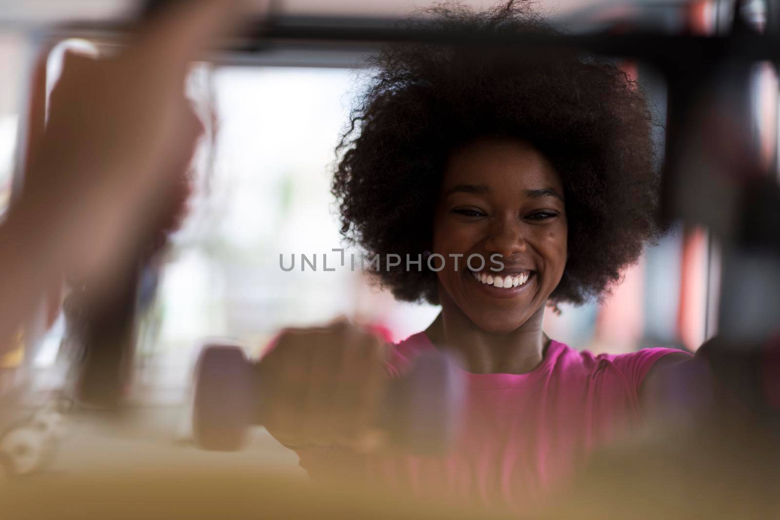 happy healthy african american woman working out in a crossfit gym on weight loss with dumbbells