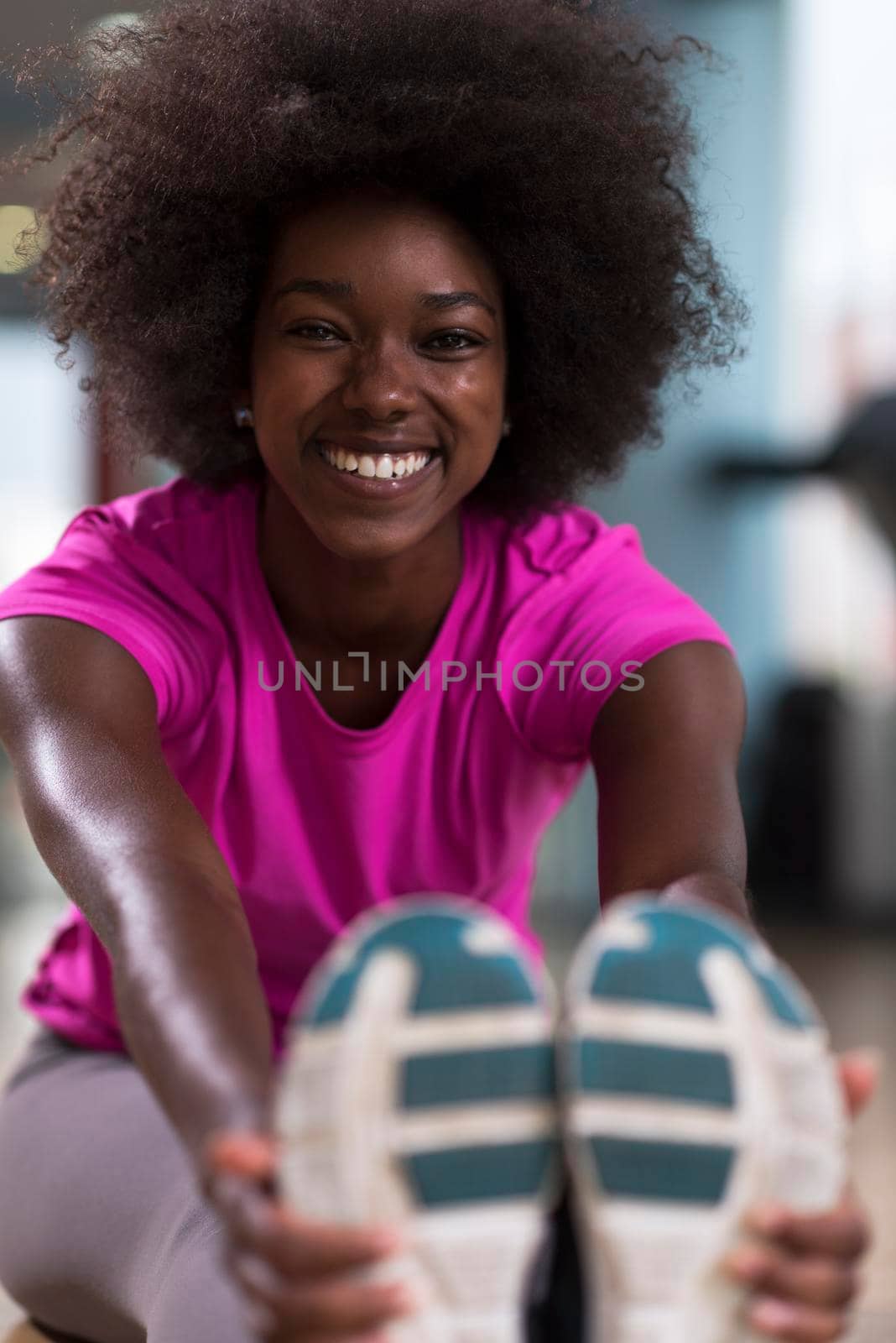 woman in a gym stretching and warming up before workout by dotshock