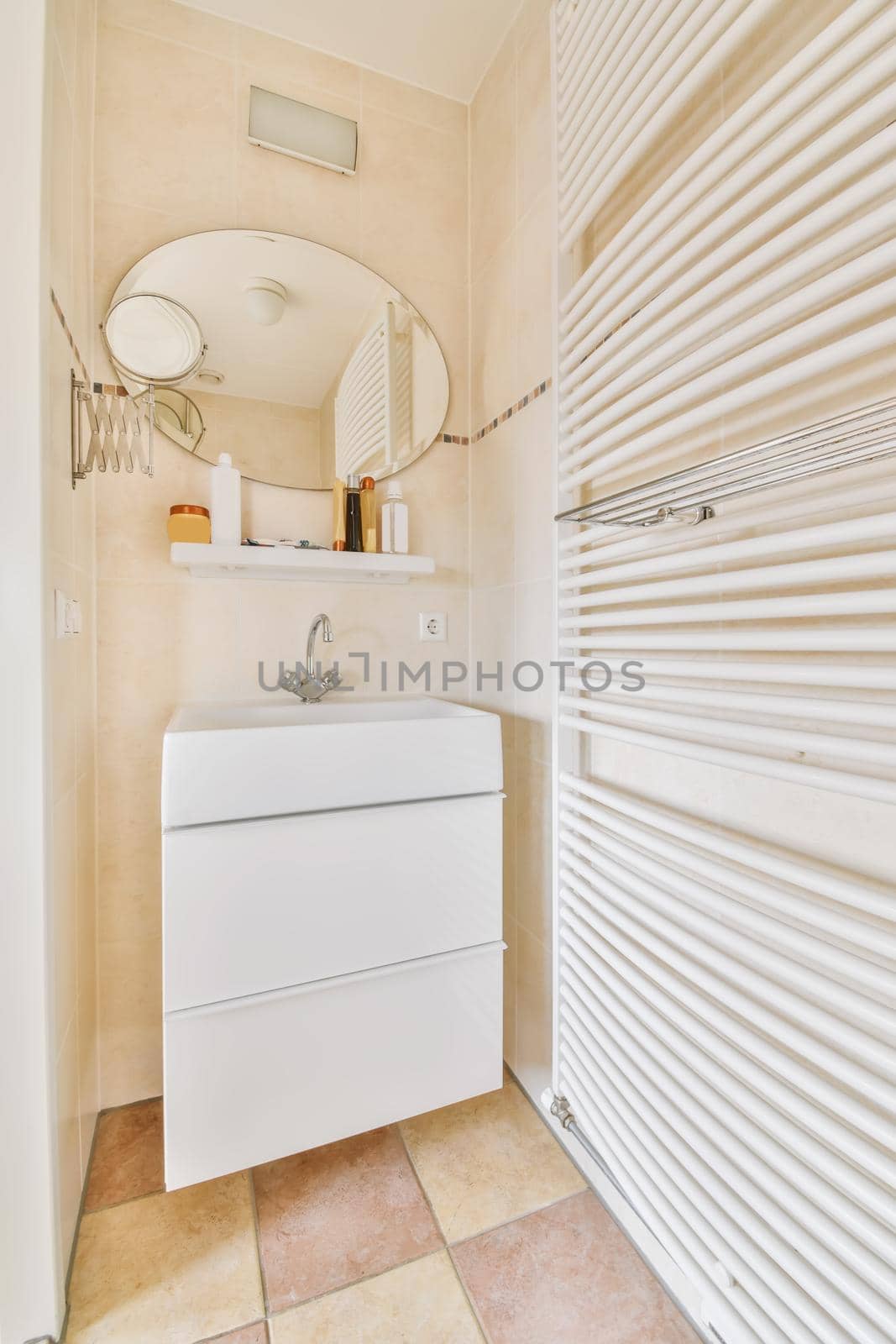 A lovely washbasin with a round mirror with shelves and a radiator near