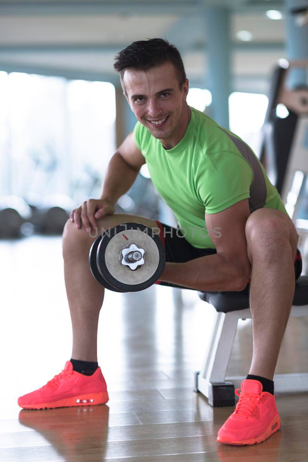 young handsome man working out with dumbbells in a fitness gym