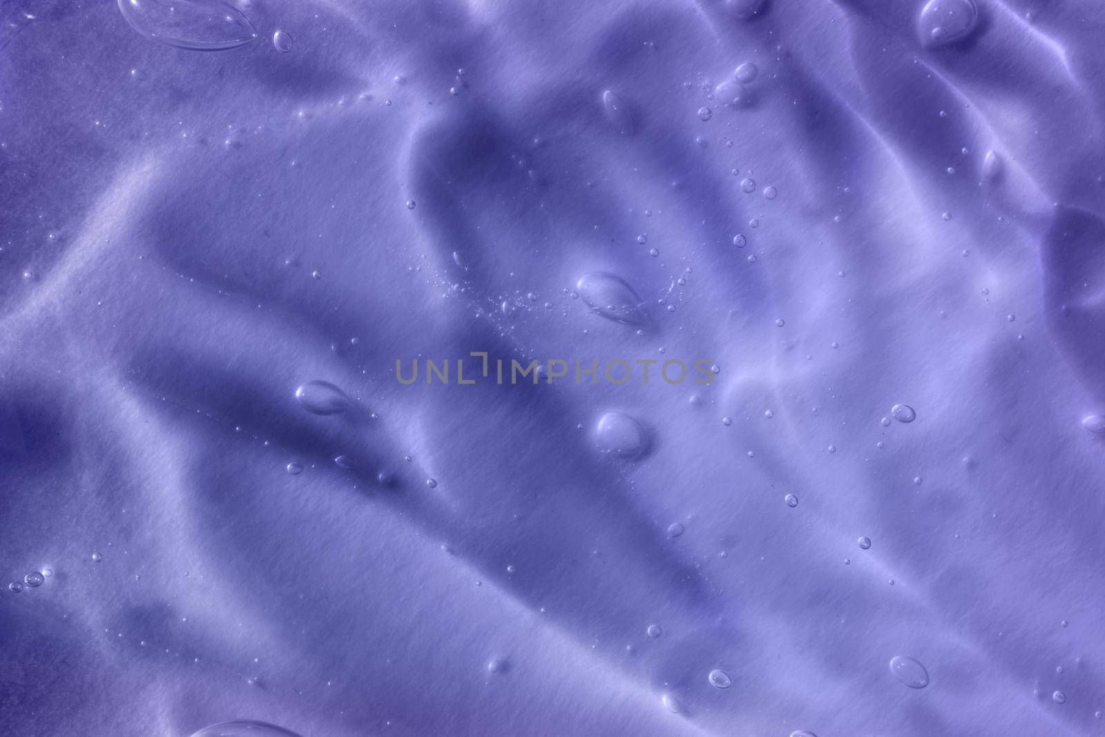 Color of the year 2022. Texture of transparent light violet blue gel with air bubbles and waves on soft background. Concept of skin moisturizing and prevention of covid. Liquid beauty product closeup