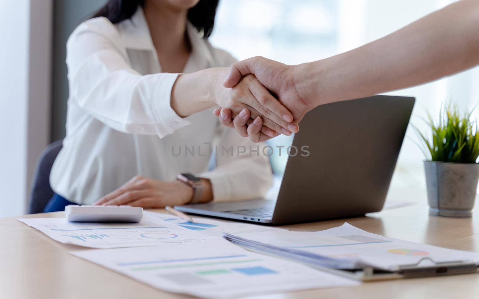 Businesswoman or bank officer Shaking hands after agreeing to work together successfully in office. Concept of Professional executive partners working at the workplace. by pravinrus