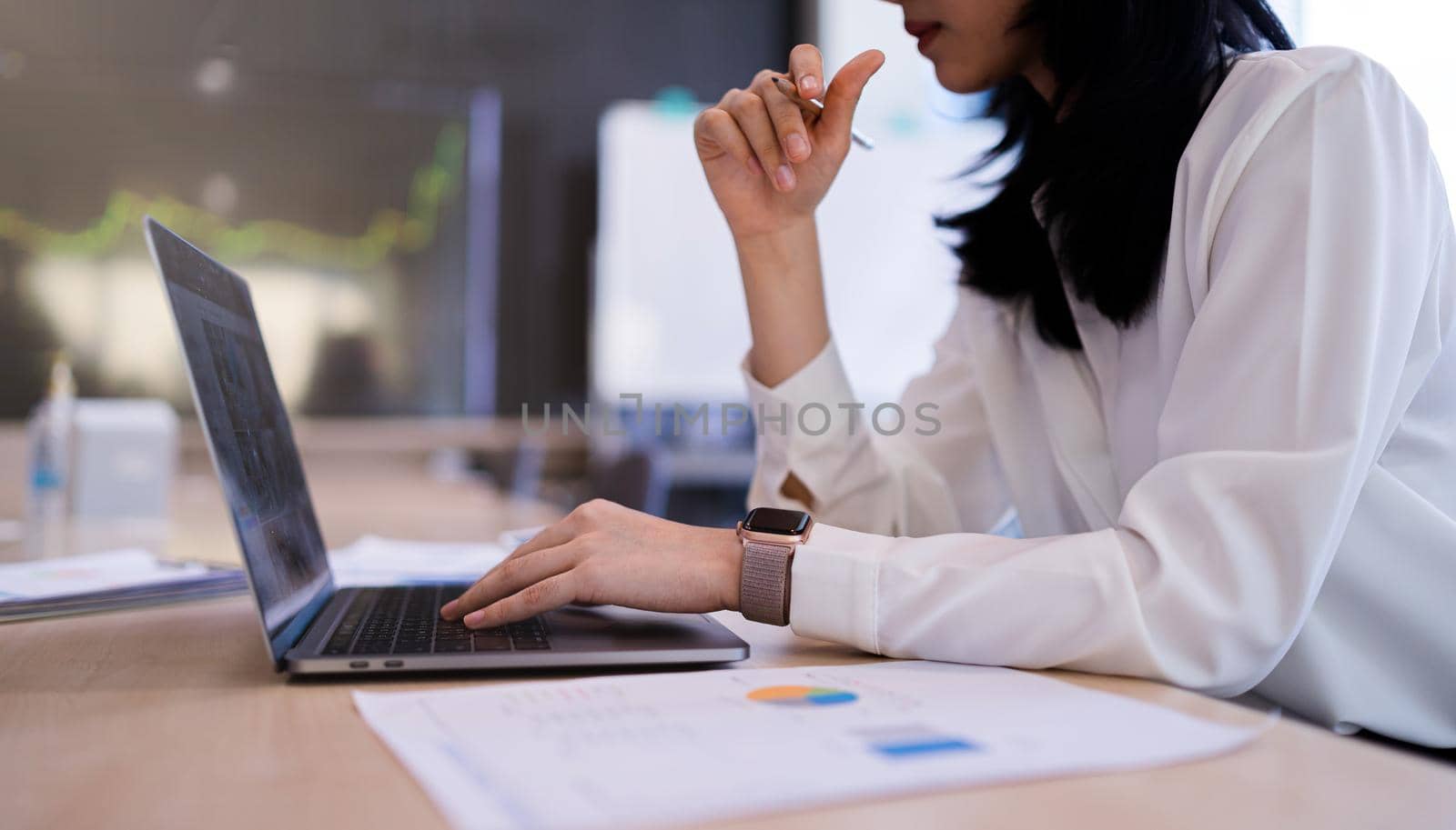 An office lady or bank officer is working hard on the laptop computer on company statistics, income, profit, loss at the workplace.