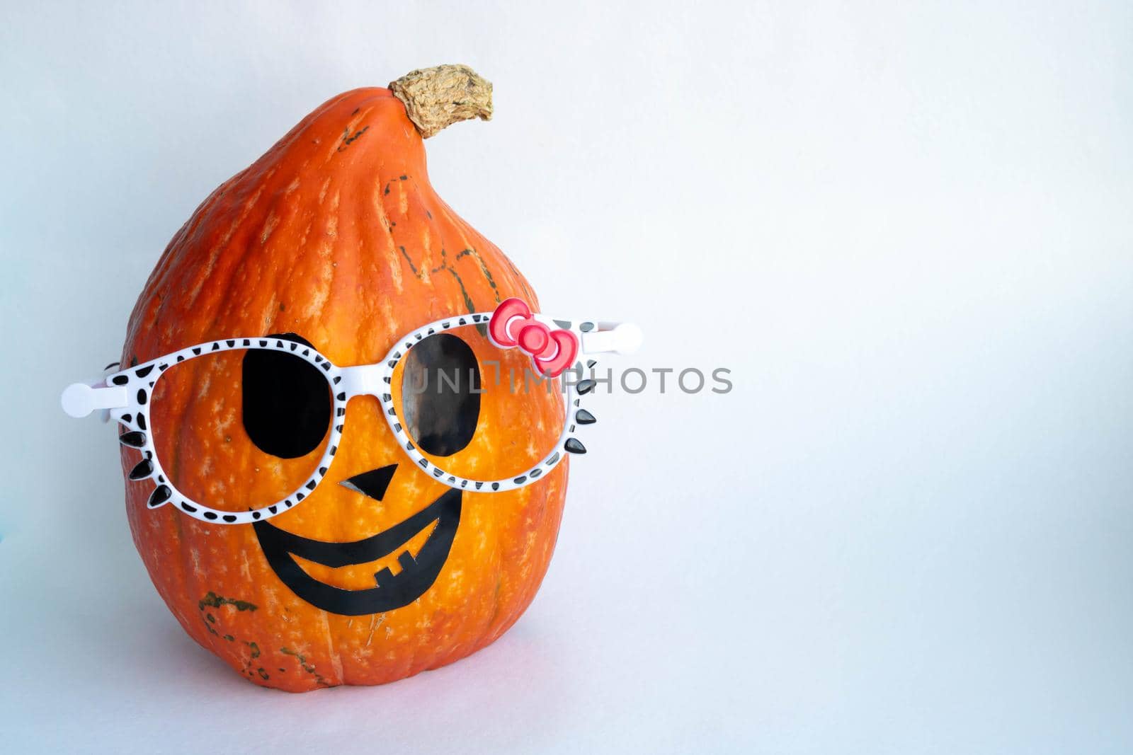 A smiling orange pumpkin with glasses on a white background. Halloween Concept.