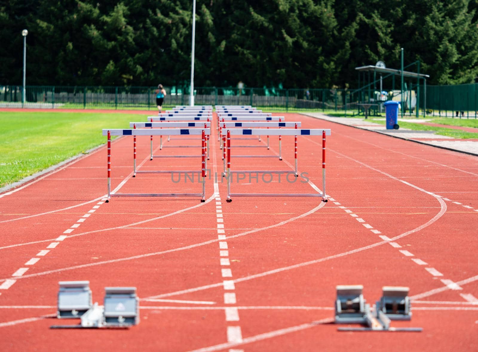 Hurdle on the sprint lane with starting blocks against blurry background. Stadium with two hurdles training tracks. 