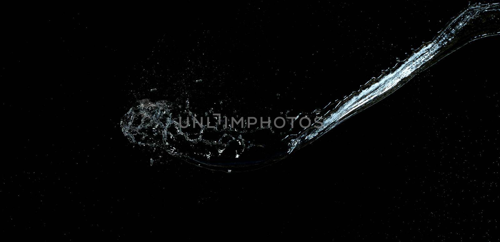 jet of transparent water with small drops and splashes on a black background
