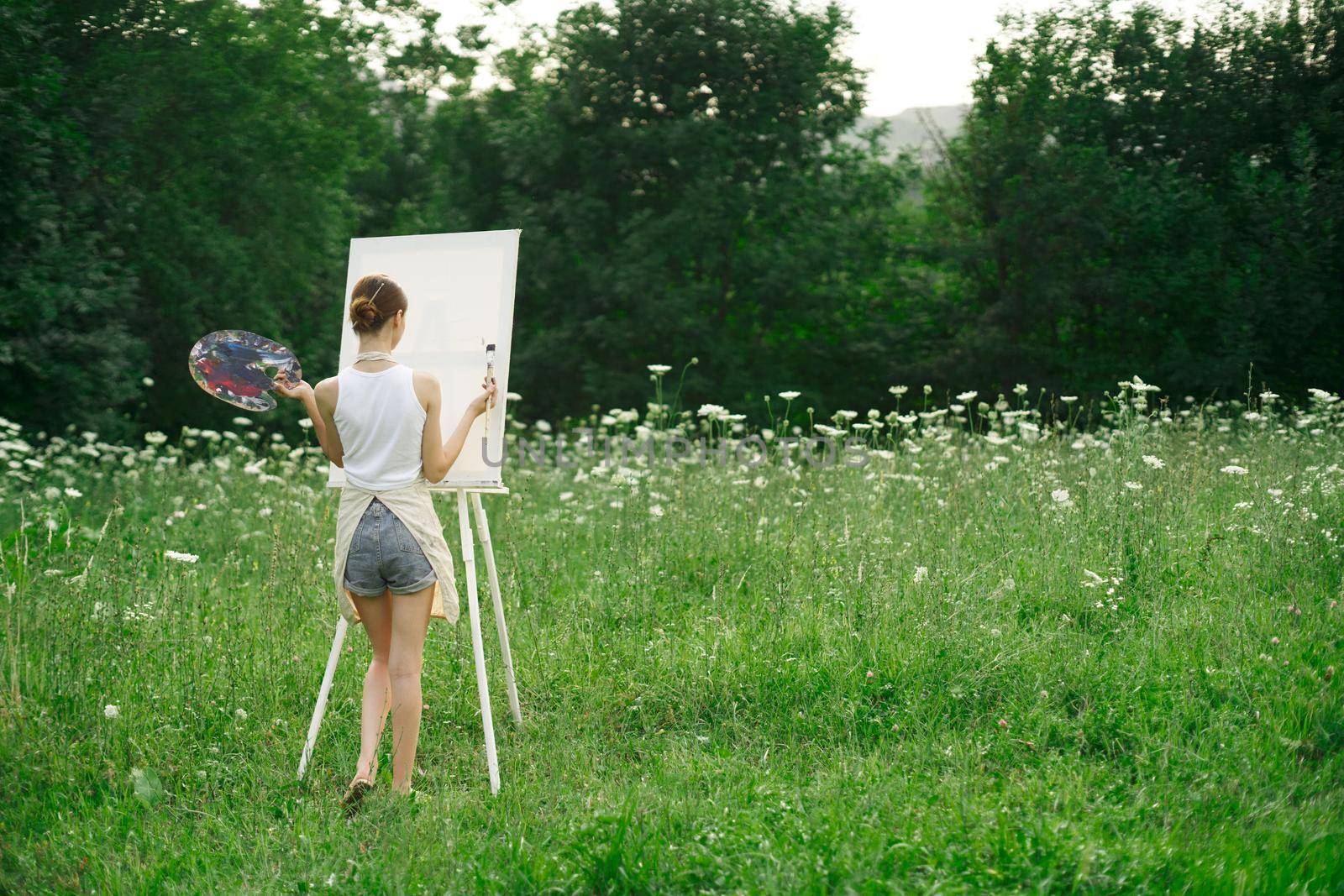 woman artist in aprons paint palette easel nature. High quality photo