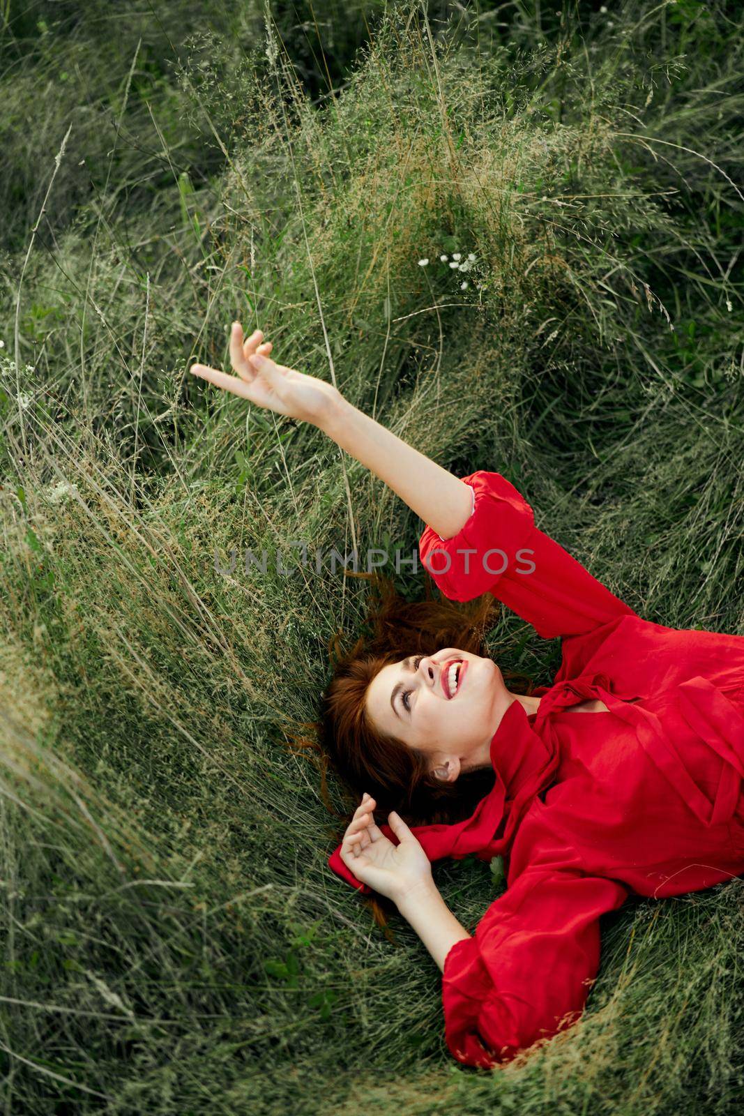 woman in red dress lies on the grass fresh air nature freedom. High quality photo