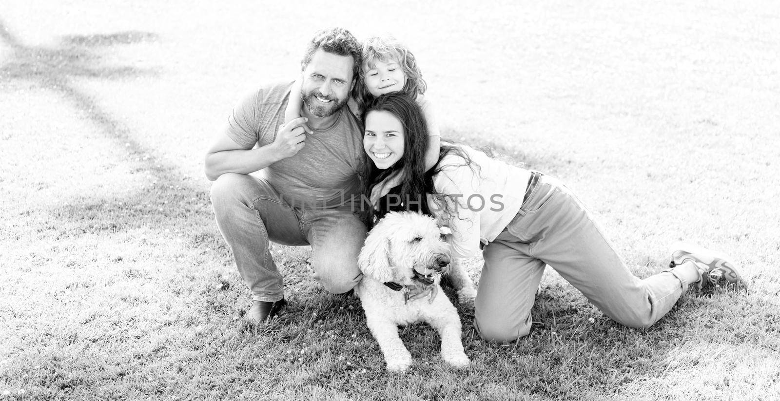 happy family portrait of mom dad and kid boy playing with pet in park on green grass, togetherness.