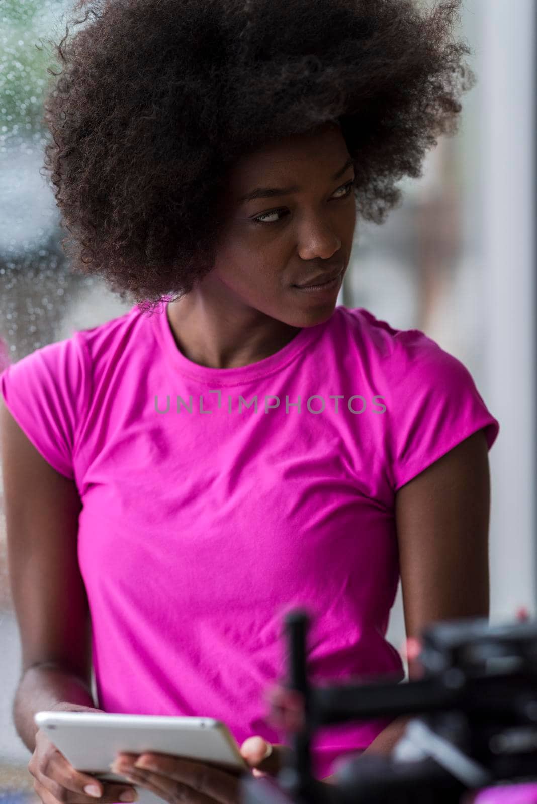 beautiful african american woman using tablet computer from home while rain and bad weather is outdoor