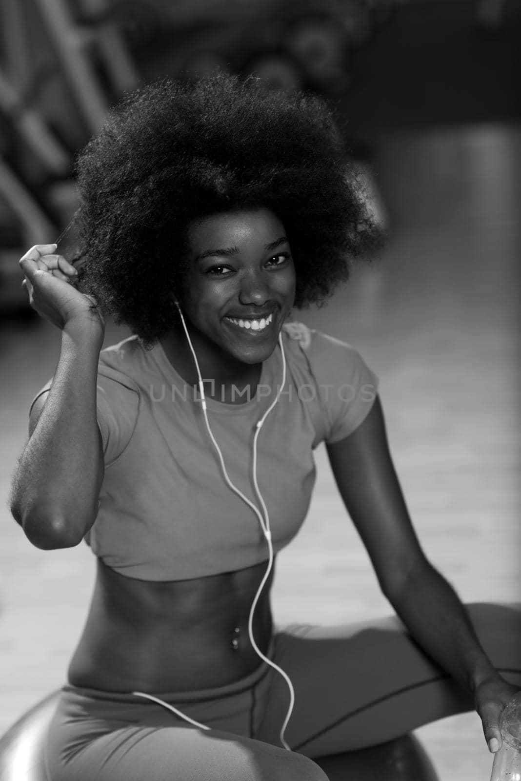 happy african american woman with a curly afro hairstyle in a  gym relaxing after pilates workout