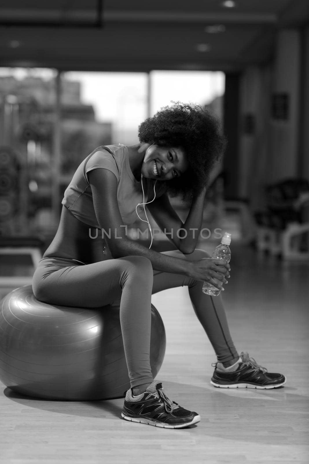 happy african american woman with a curly afro hairstyle in a  gym relaxing after pilates workout