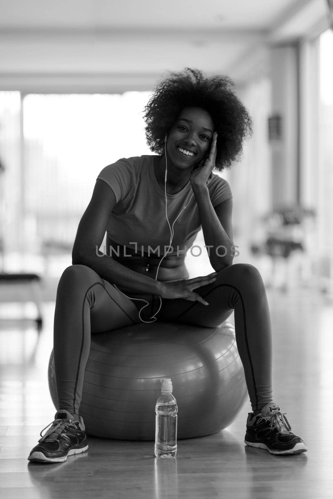 happy african american woman with a curly afro hairstyle in a  gym relaxing after pilates workout