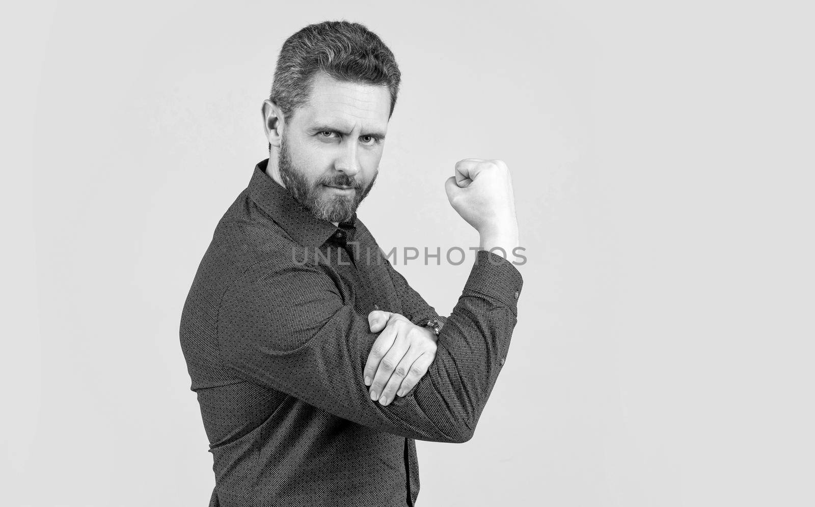 Mature man bend arm in L-shape with fist pointing upwards obscene gesture grey background, fuck you, copy space.