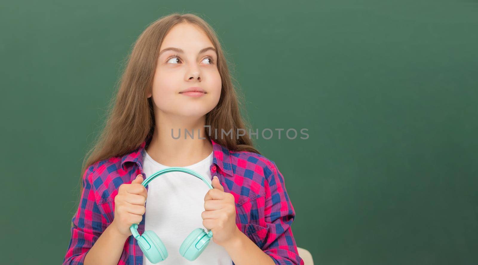 dreamy kid with earphones at blackboard, childhood.