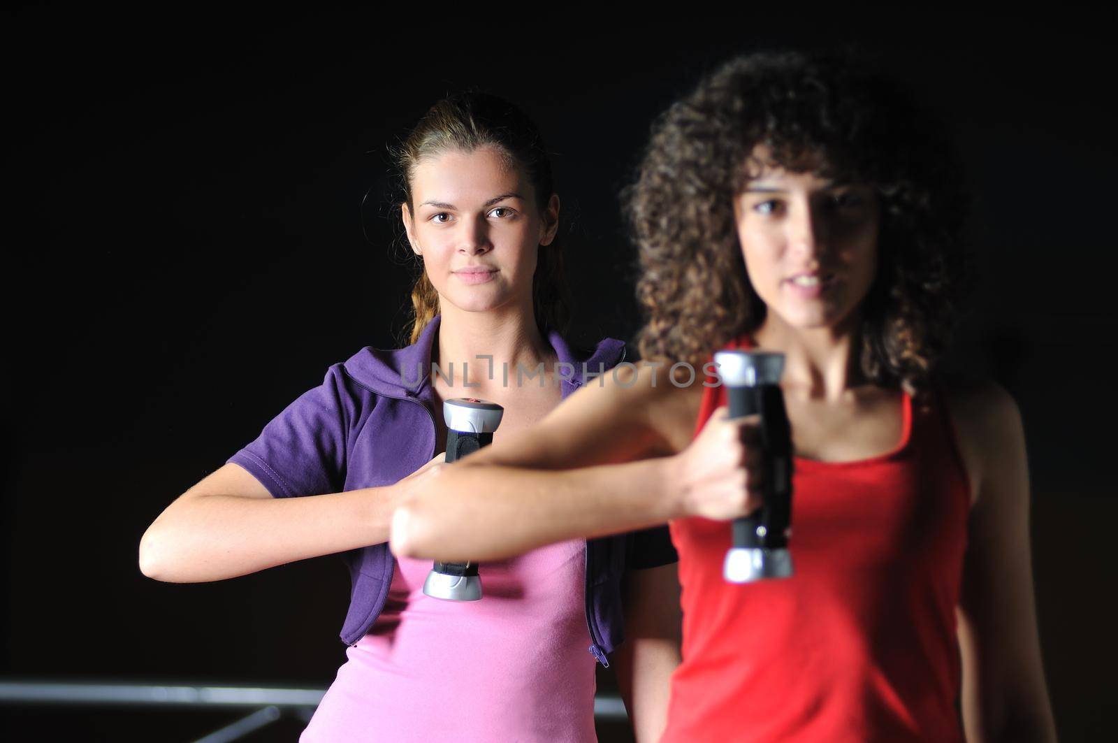 two girls working out with dumbbell in fitness club