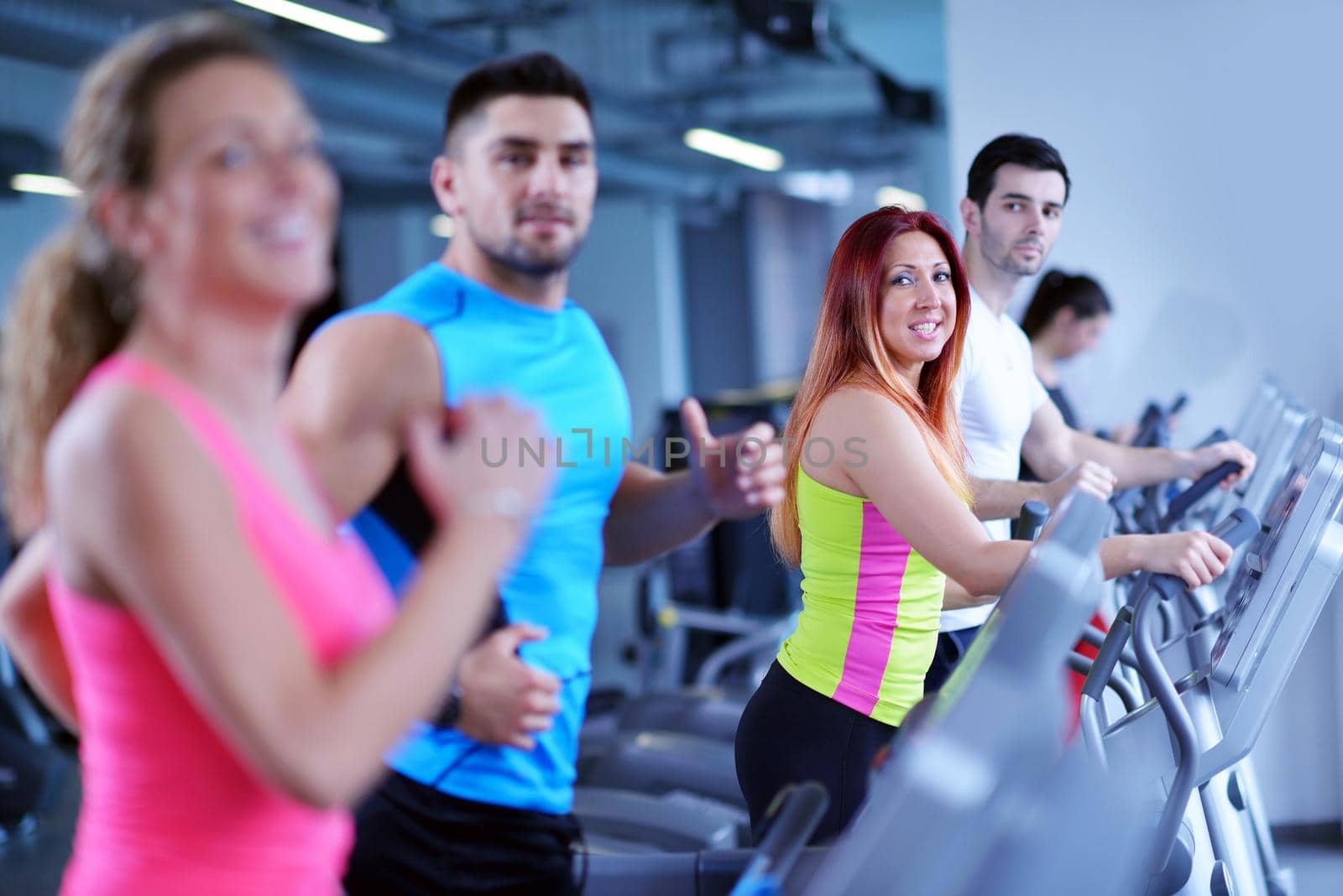 group of young people running on treadmills in modern sport  gym