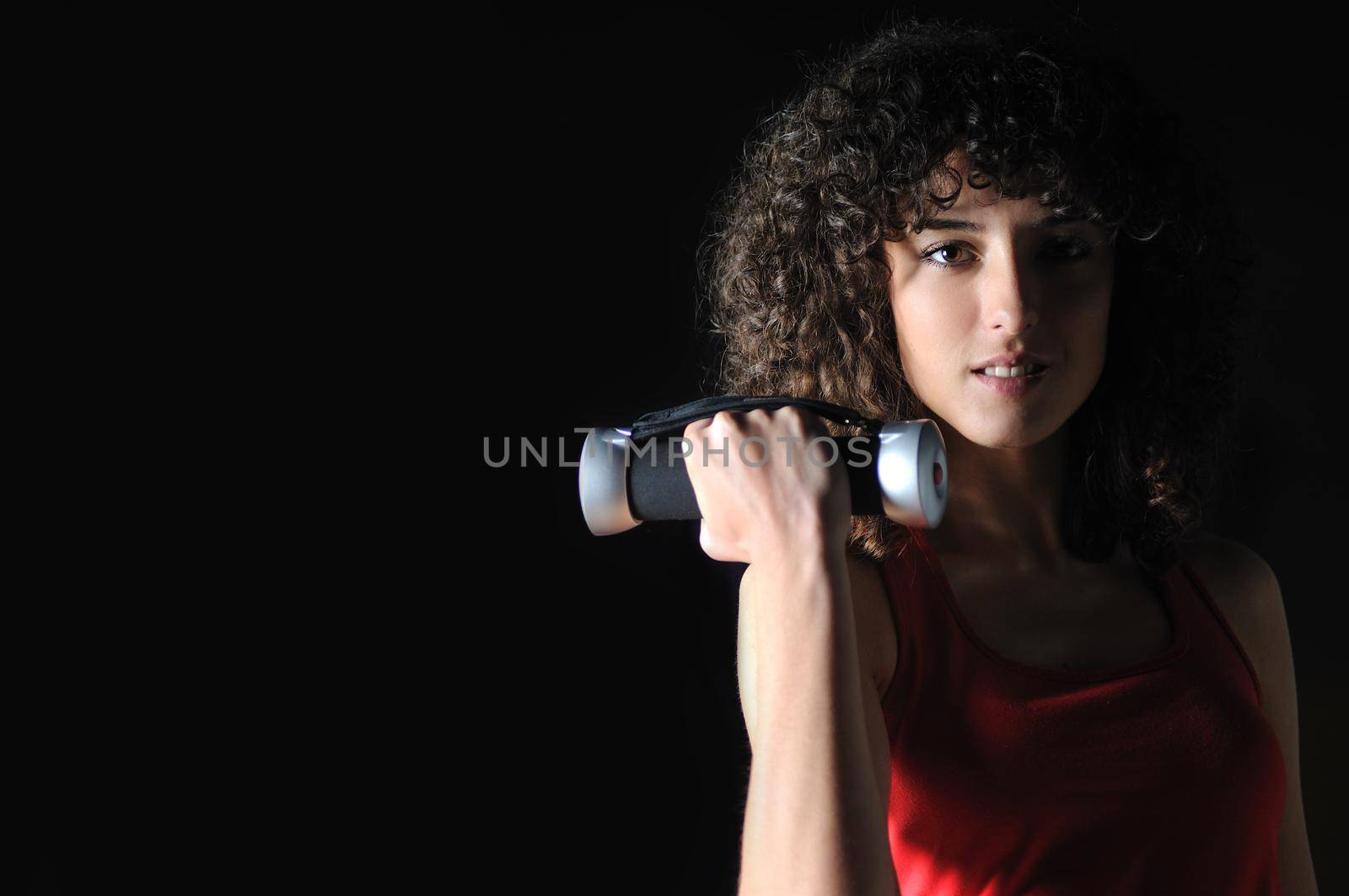 youg woman workout in fitness club with dumbbell by dotshock