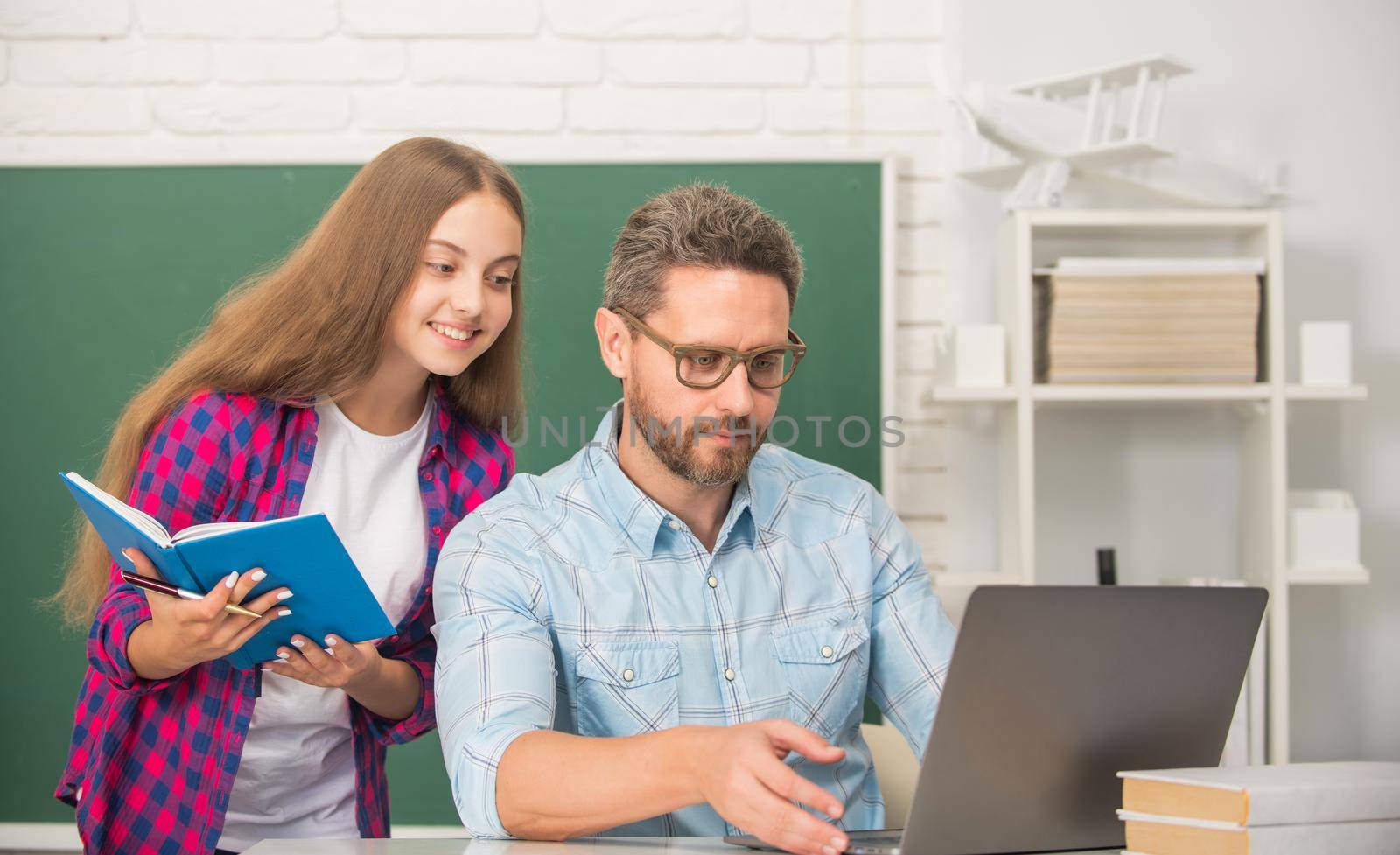 busy father and child study at school with book and laptop on blackboard background, parenthood.
