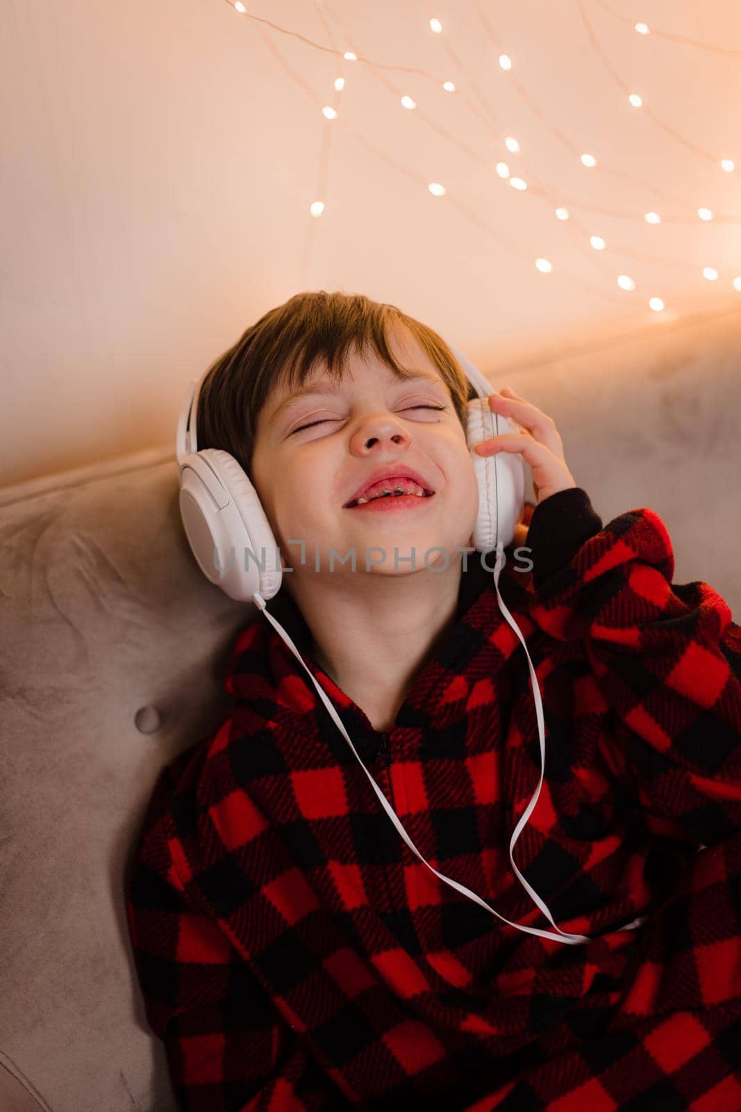 A boy with headphones is lying on the sofa lifestyle. The boy listens to music. New Year's mood.