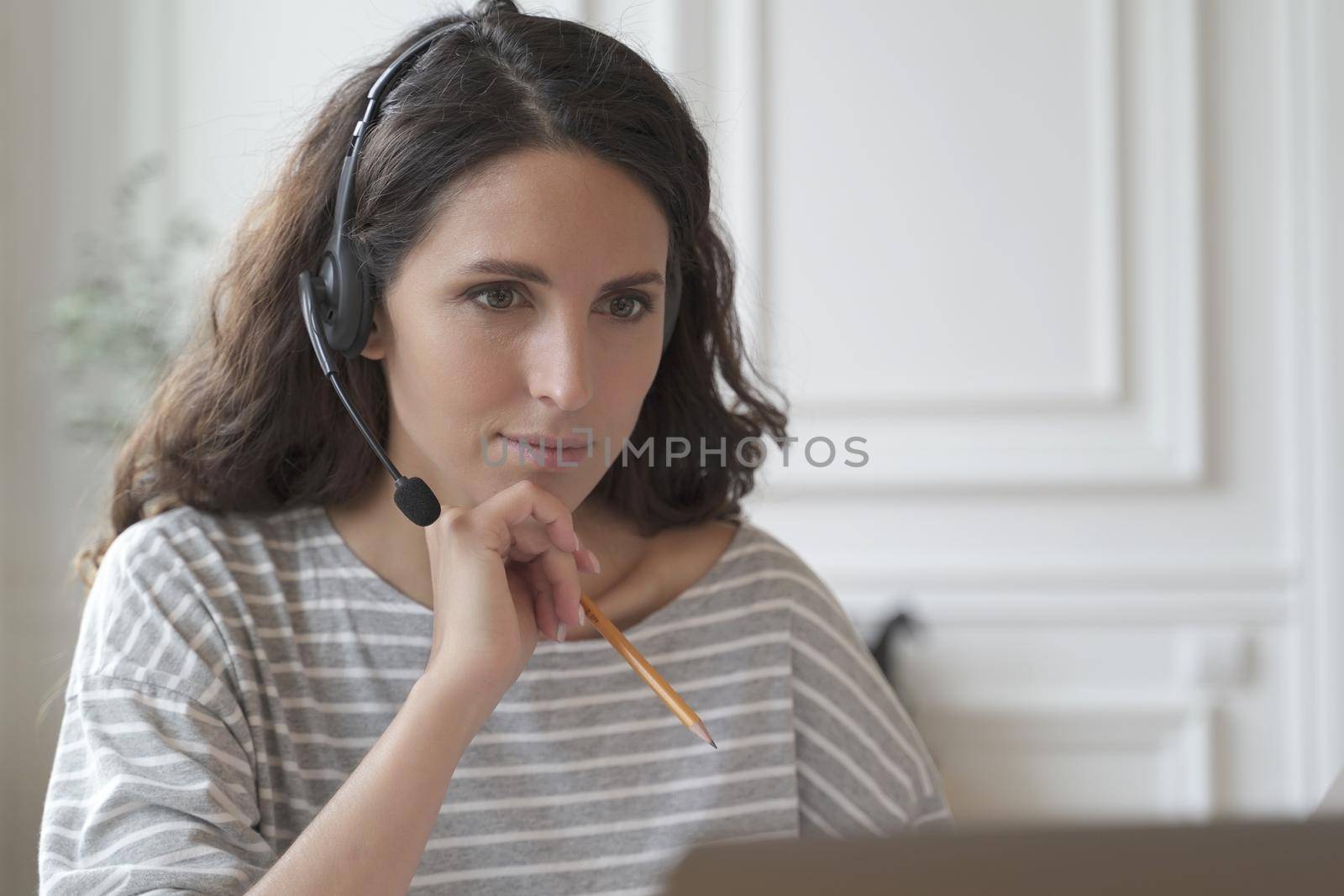 Focused entrepreneur in headphones attentively listens educational vebinar looking at laptop screen by vkstock