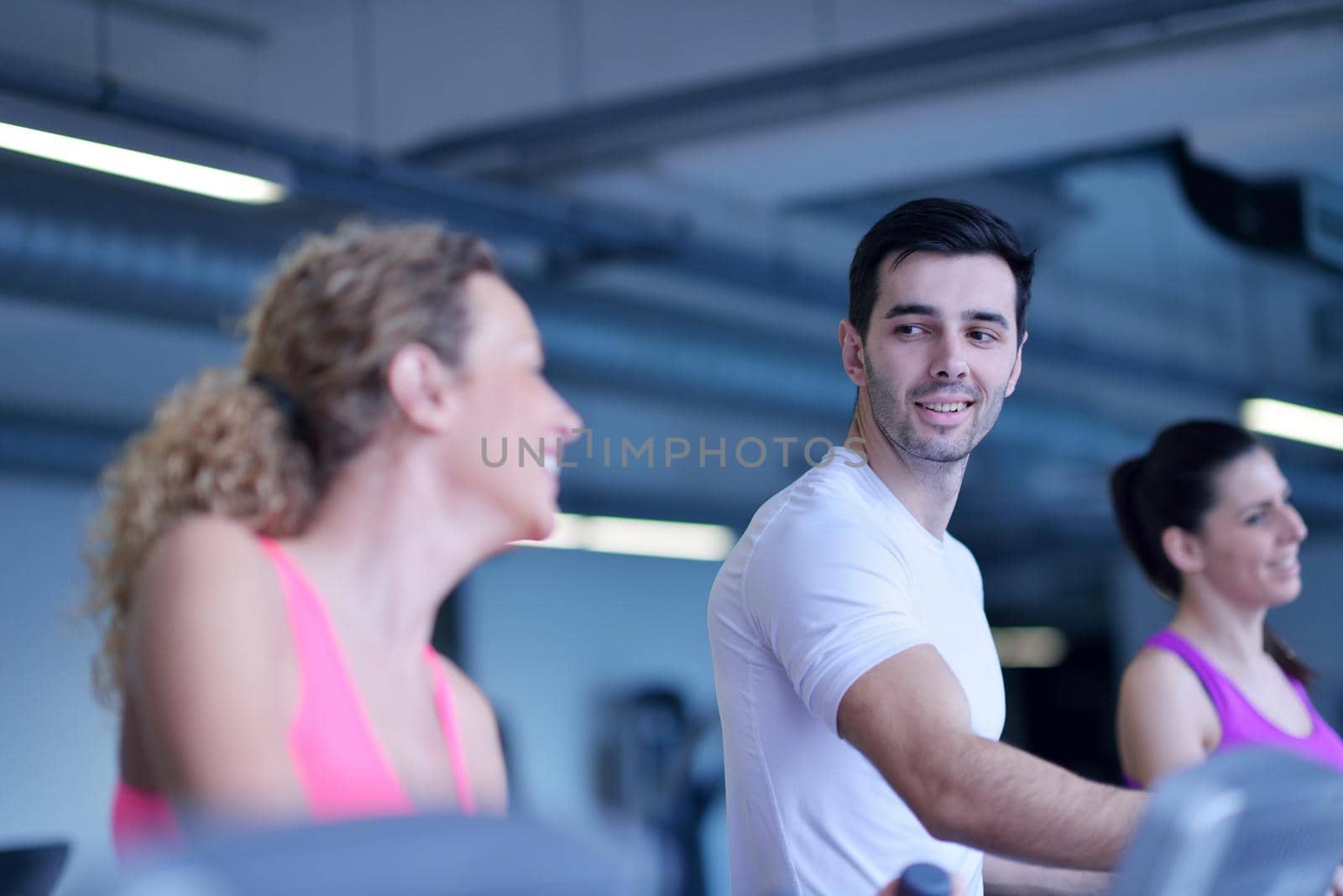 group of young people running on treadmills in modern sport  gym