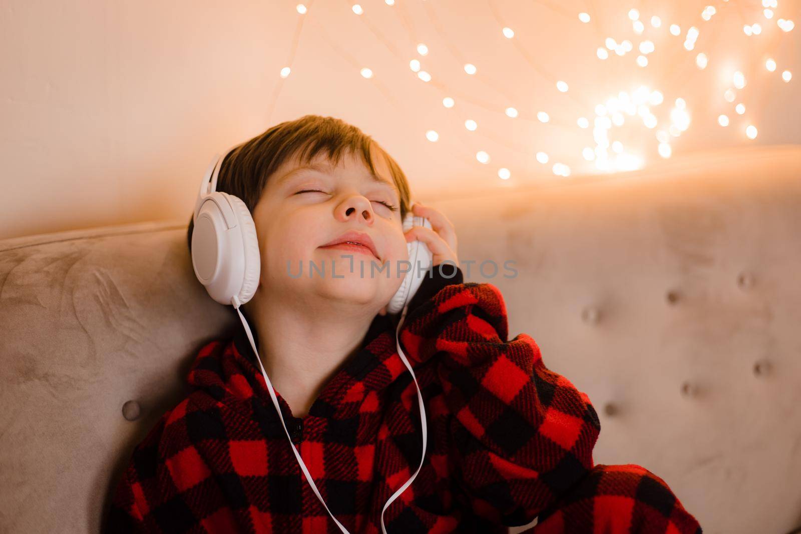 A boy with headphones is lying on the sofa lifestyle. The boy listens to music. New Year's mood.