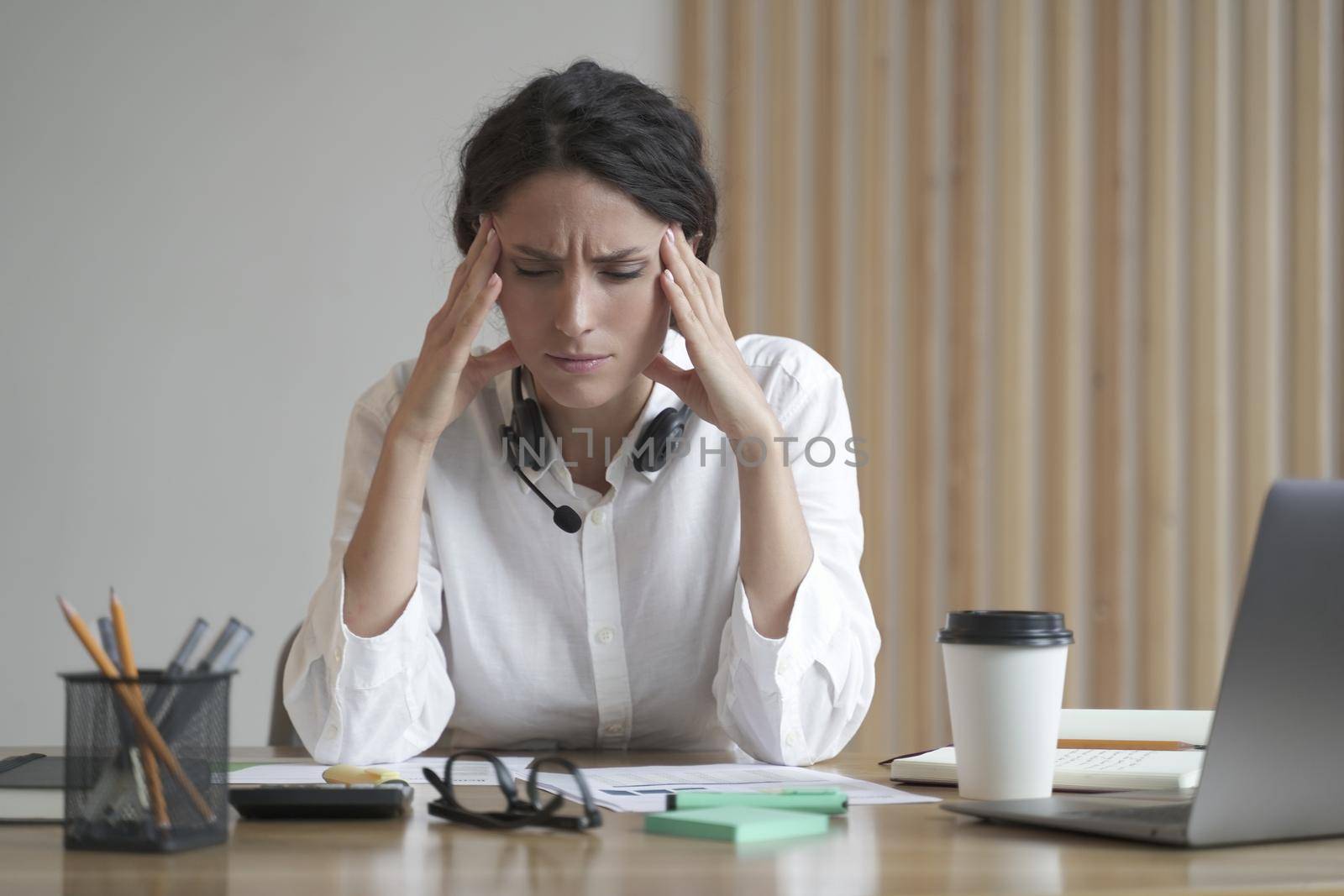 Stressed entrepreneur lady suffering from headache massaging temples while sitting at home office by vkstock