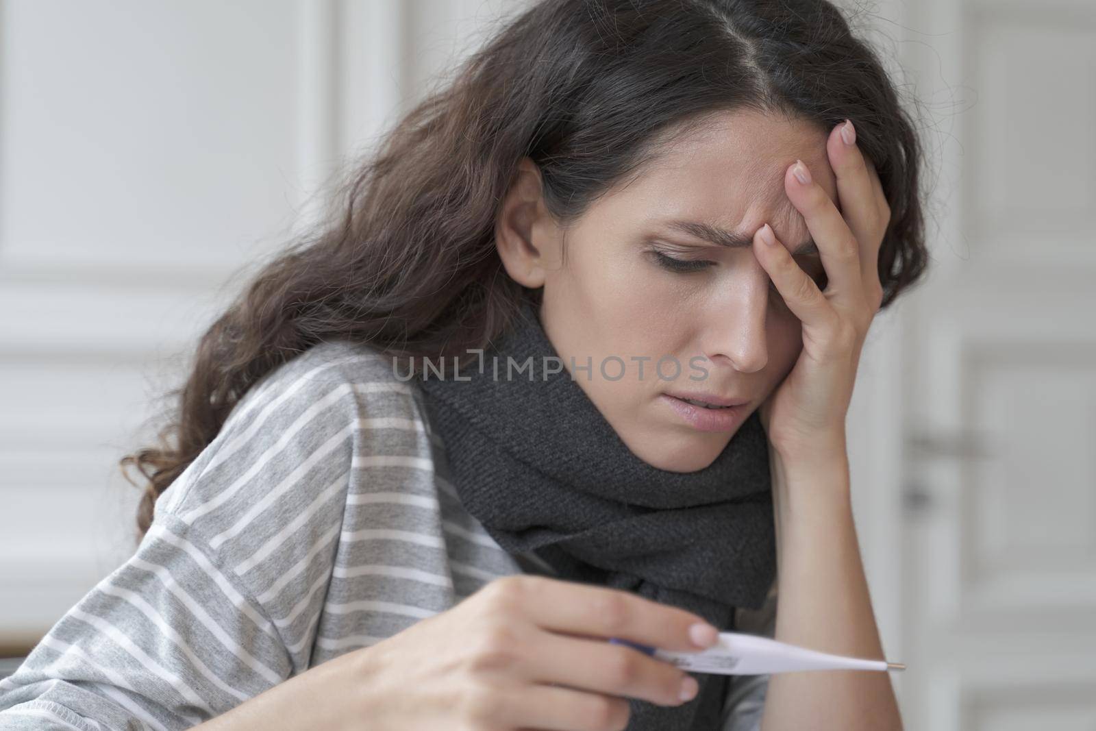 Sick diseased hispanic woman with headache measuring checking temperature at home by vkstock