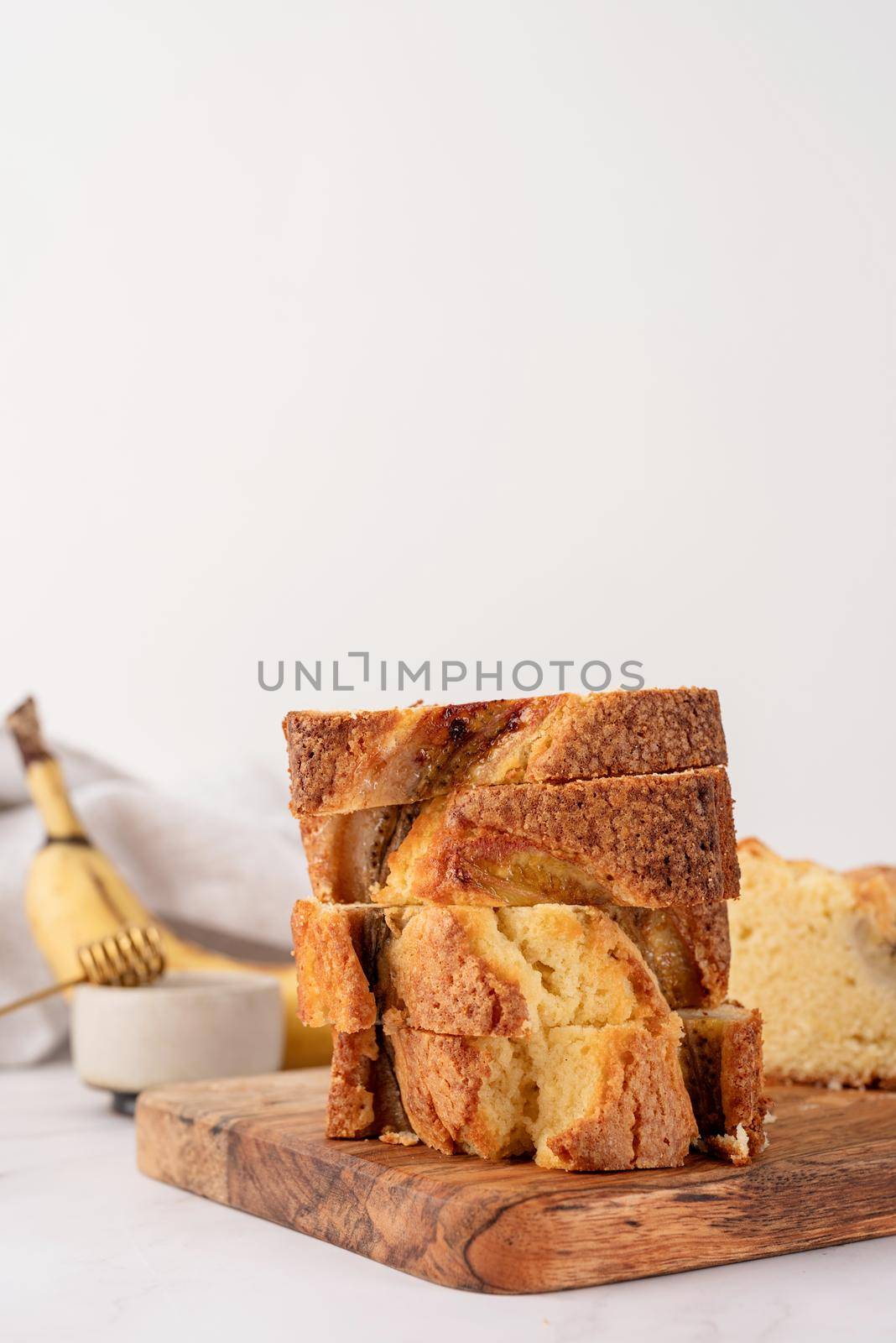 Baking and cooking. Front view of sliced banana bread on light concrete background with honey. Delicious sweet dessert or snack, morning breakfast. Copy space