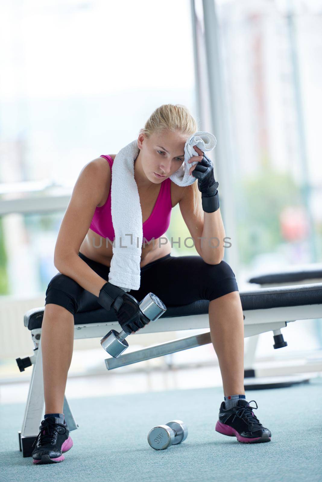 halethy young woman exercise with dumbells and relaxing on banch in fitness gym